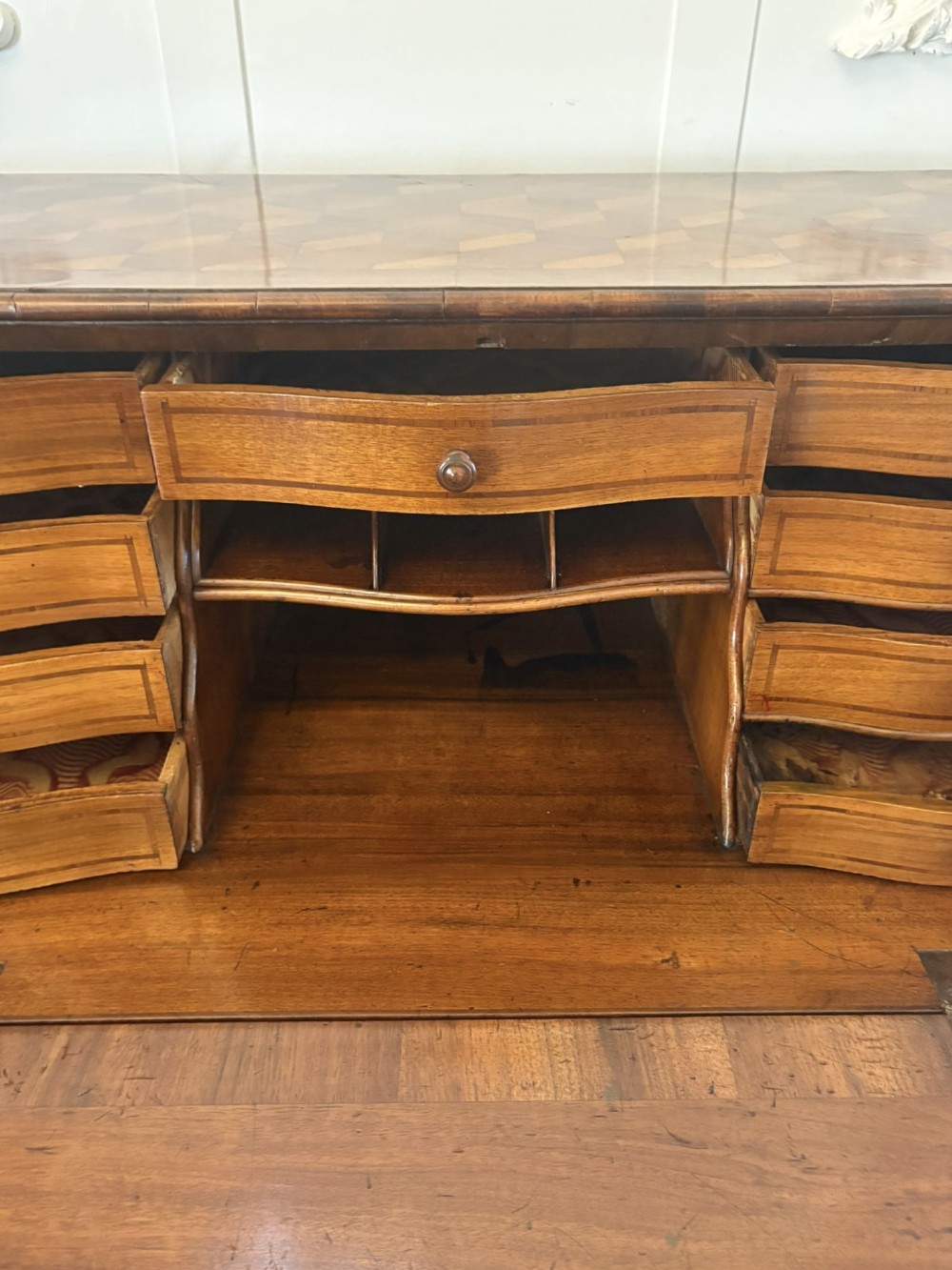 An 18th-century French walnut bureau featuring geometric cubic parquetry inlay, a sloped fall-front lid, curved bombe sides, and brass handles. View V