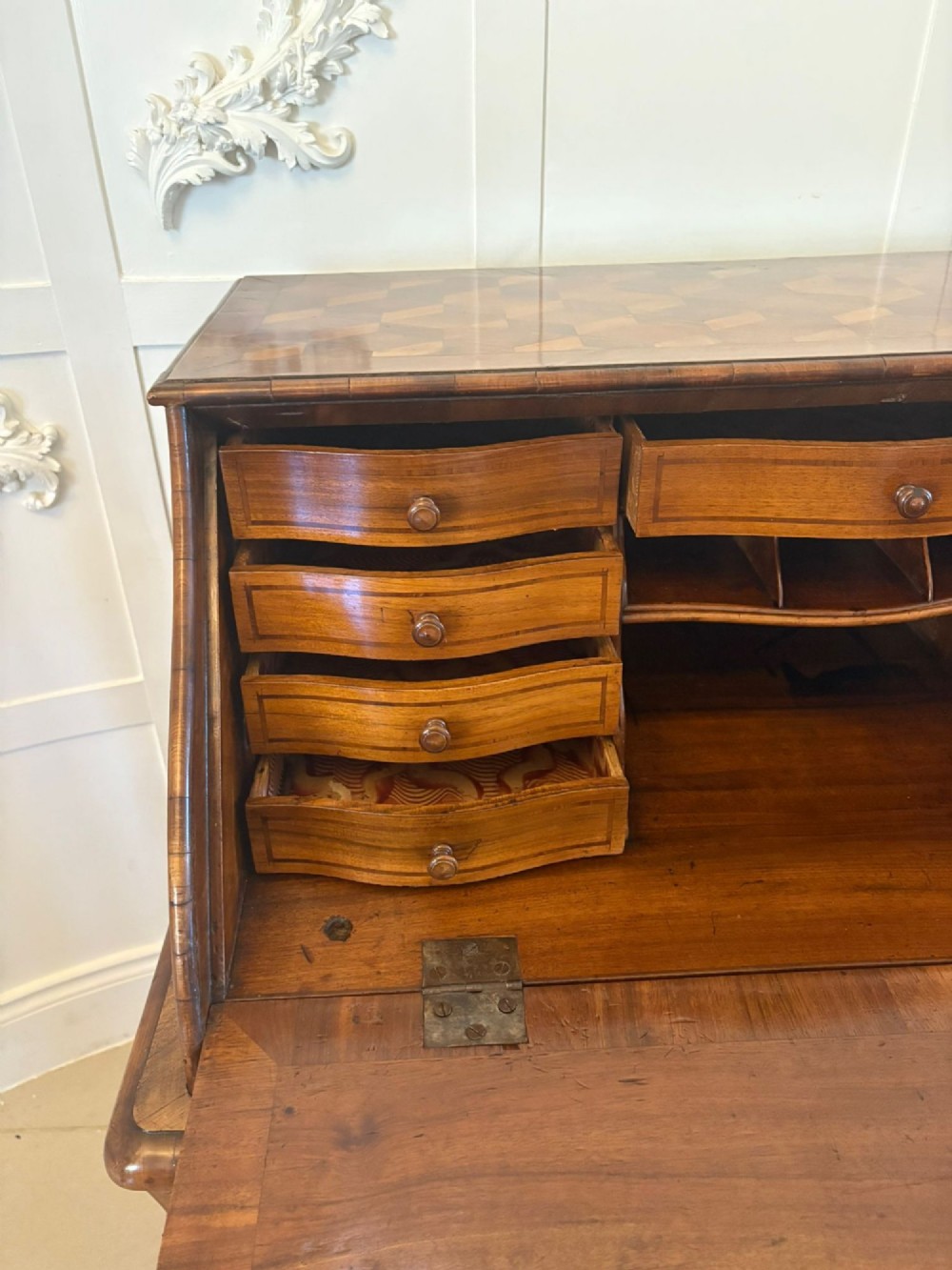 An 18th-century French walnut bureau featuring geometric cubic parquetry inlay, a sloped fall-front lid, curved bombe sides, and brass handles. View VI