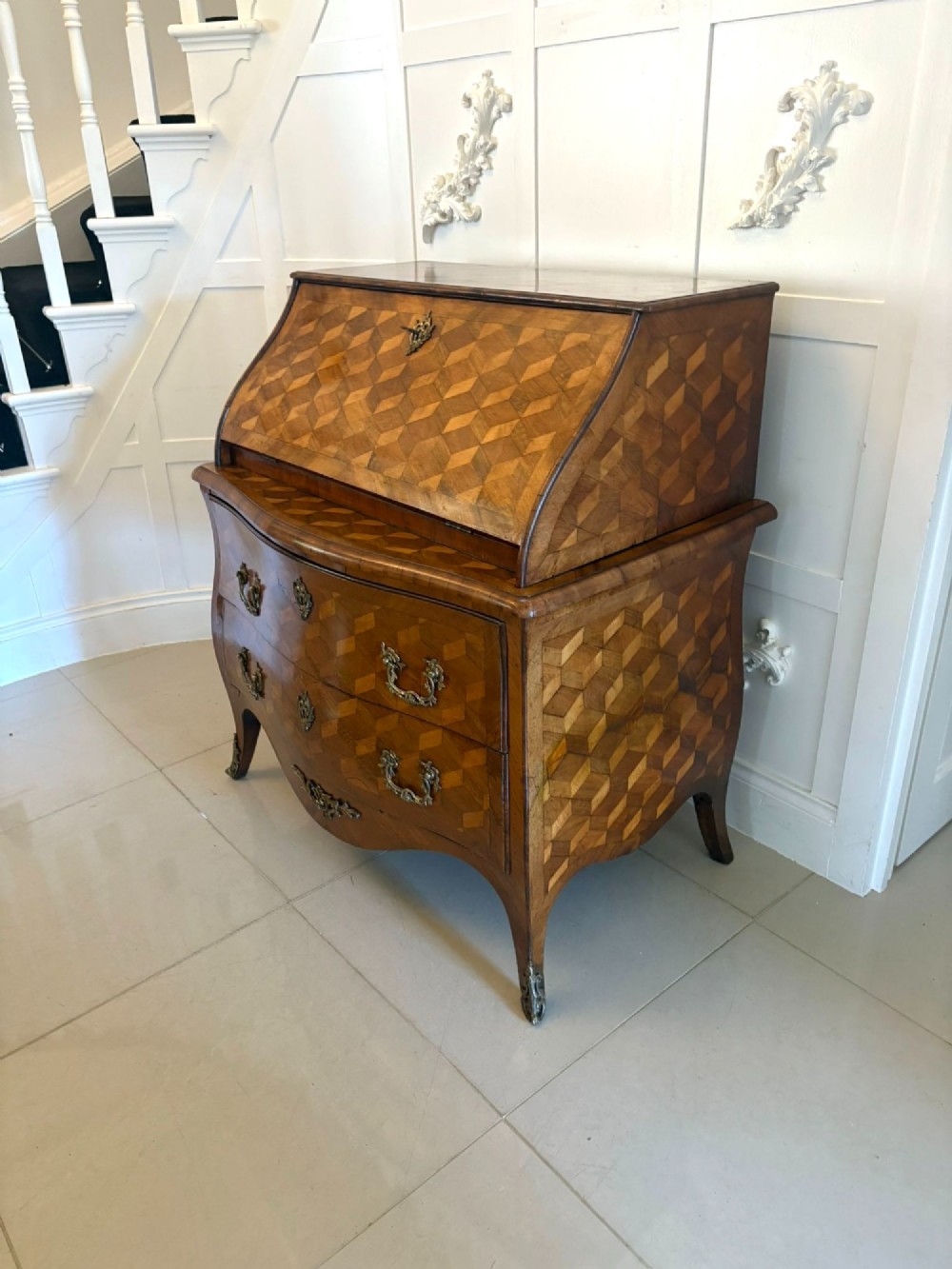 An 18th-century French walnut bureau featuring geometric cubic parquetry inlay, a sloped fall-front lid, curved bombe sides, and brass handles. View VII