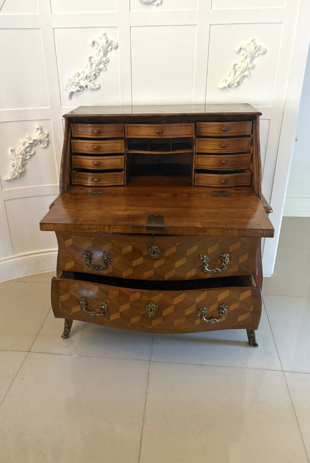 An 18th-century French walnut bureau featuring geometric cubic parquetry inlay, a sloped fall-front lid, curved bombe sides, and brass handles. View VIII