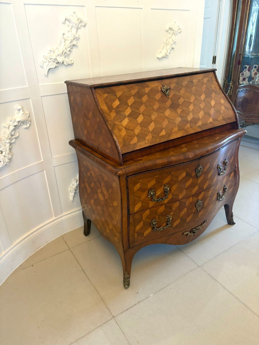 An 18th-century French walnut bureau featuring geometric cubic parquetry inlay, a sloped fall-front lid, curved bombe sides, and brass handles. View X