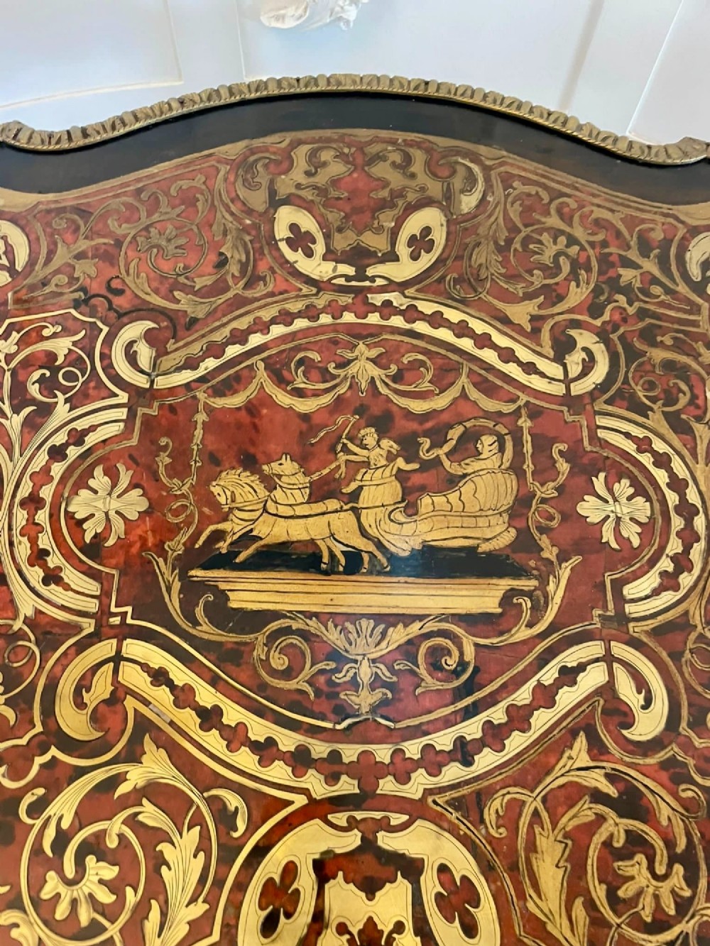An antique French Louis XV style centre table featuring red tortoiseshell and brass Boulle marquetry, serpentine top, ebonised timber, and cast ormolu mounts on cabriole legs. View VI