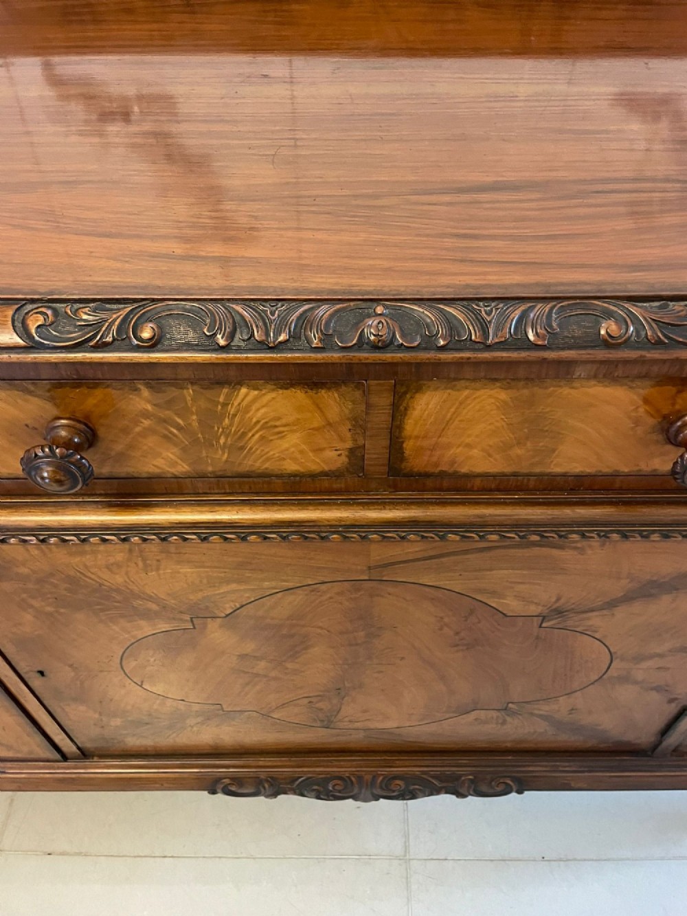 An antique burr walnut sideboard featuring quarter-veneered panel doors, carved edge mouldings, drawers with wooden knobs, and cabriole legs. View IV