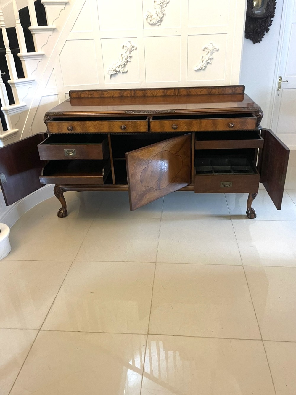 An antique burr walnut sideboard featuring quarter-veneered panel doors, carved edge mouldings, drawers with wooden knobs, and cabriole legs. View VII