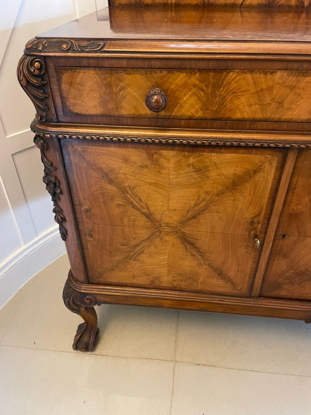An antique burr walnut sideboard featuring quarter-veneered panel doors, carved edge mouldings, drawers with wooden knobs, and cabriole legs. View XI