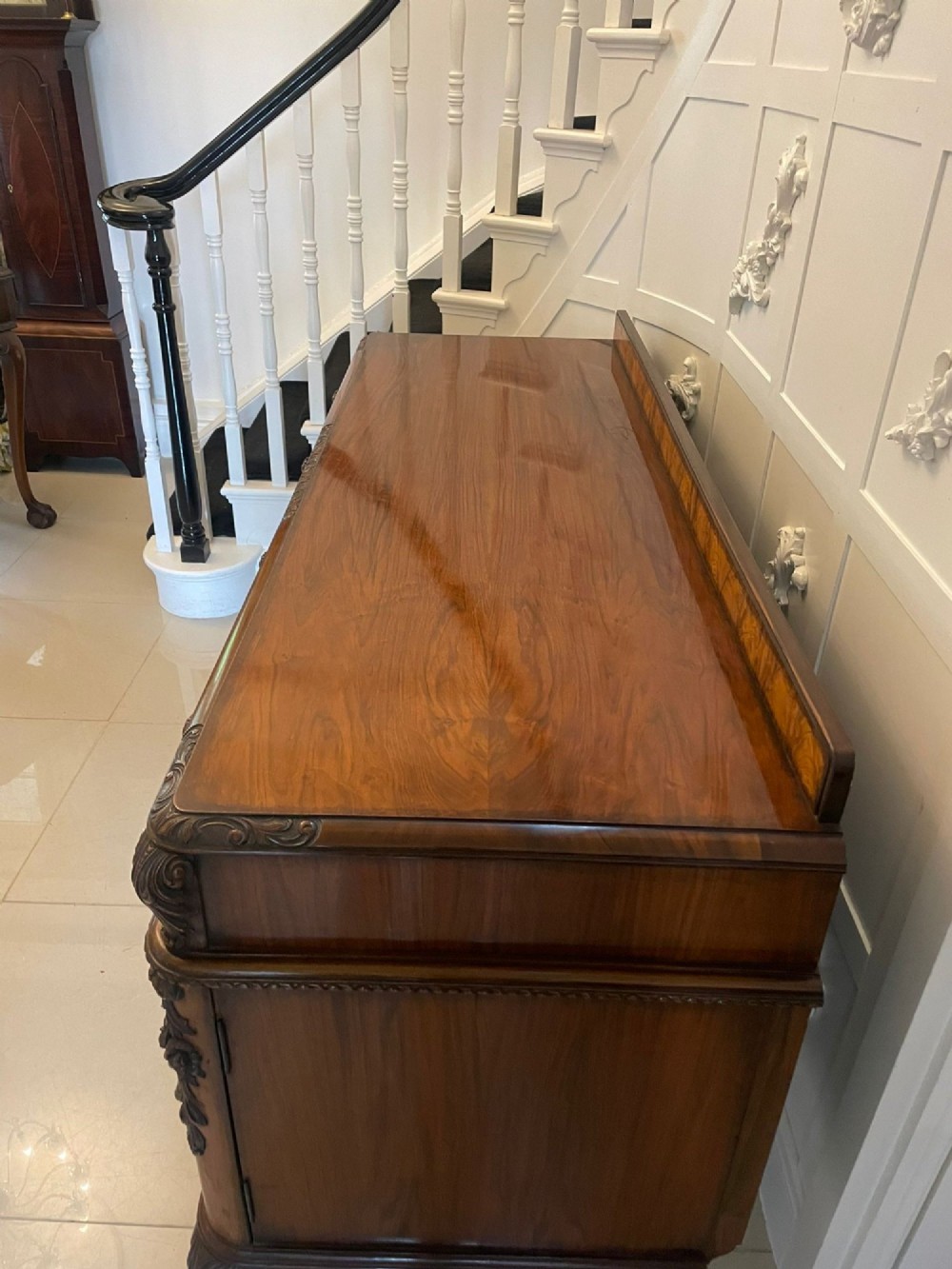 An antique burr walnut sideboard featuring quarter-veneered panel doors, carved edge mouldings, drawers with wooden knobs, and cabriole legs. View XIII