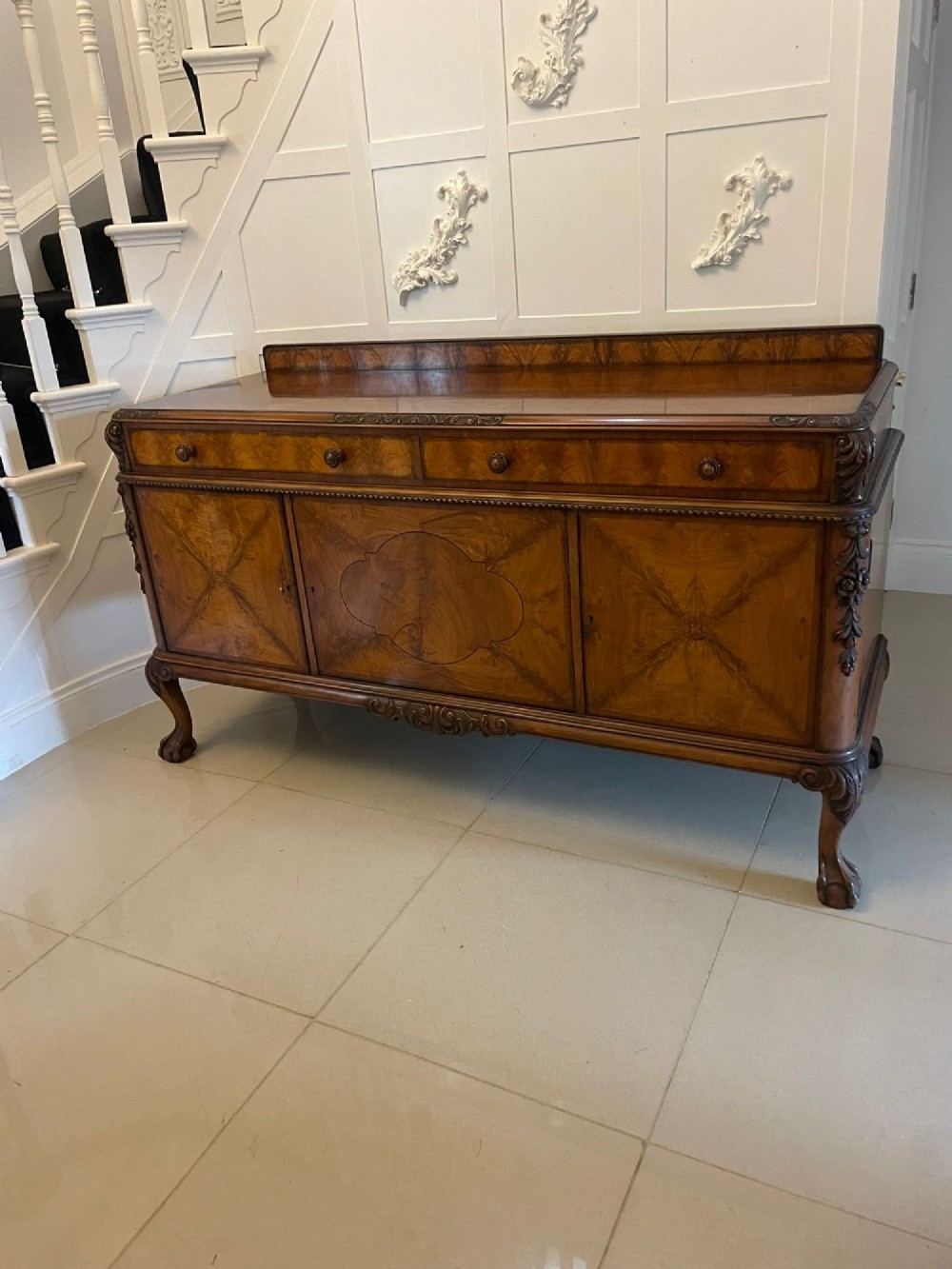 An antique burr walnut sideboard featuring quarter-veneered panel doors, carved edge mouldings, drawers with wooden knobs, and cabriole legs. View XIV