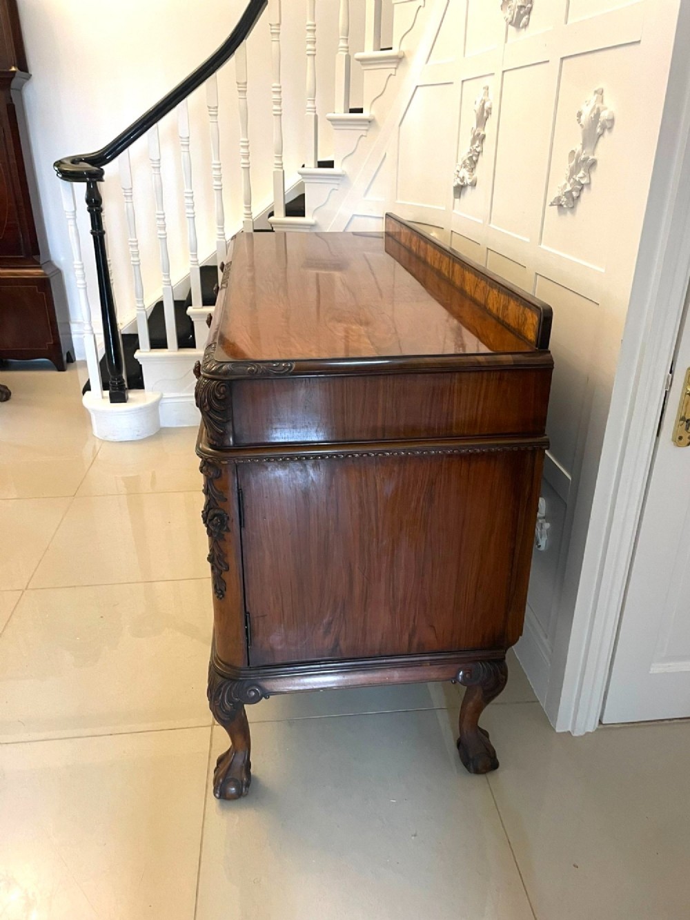 An antique burr walnut sideboard featuring quarter-veneered panel doors, carved edge mouldings, drawers with wooden knobs, and cabriole legs. View XV