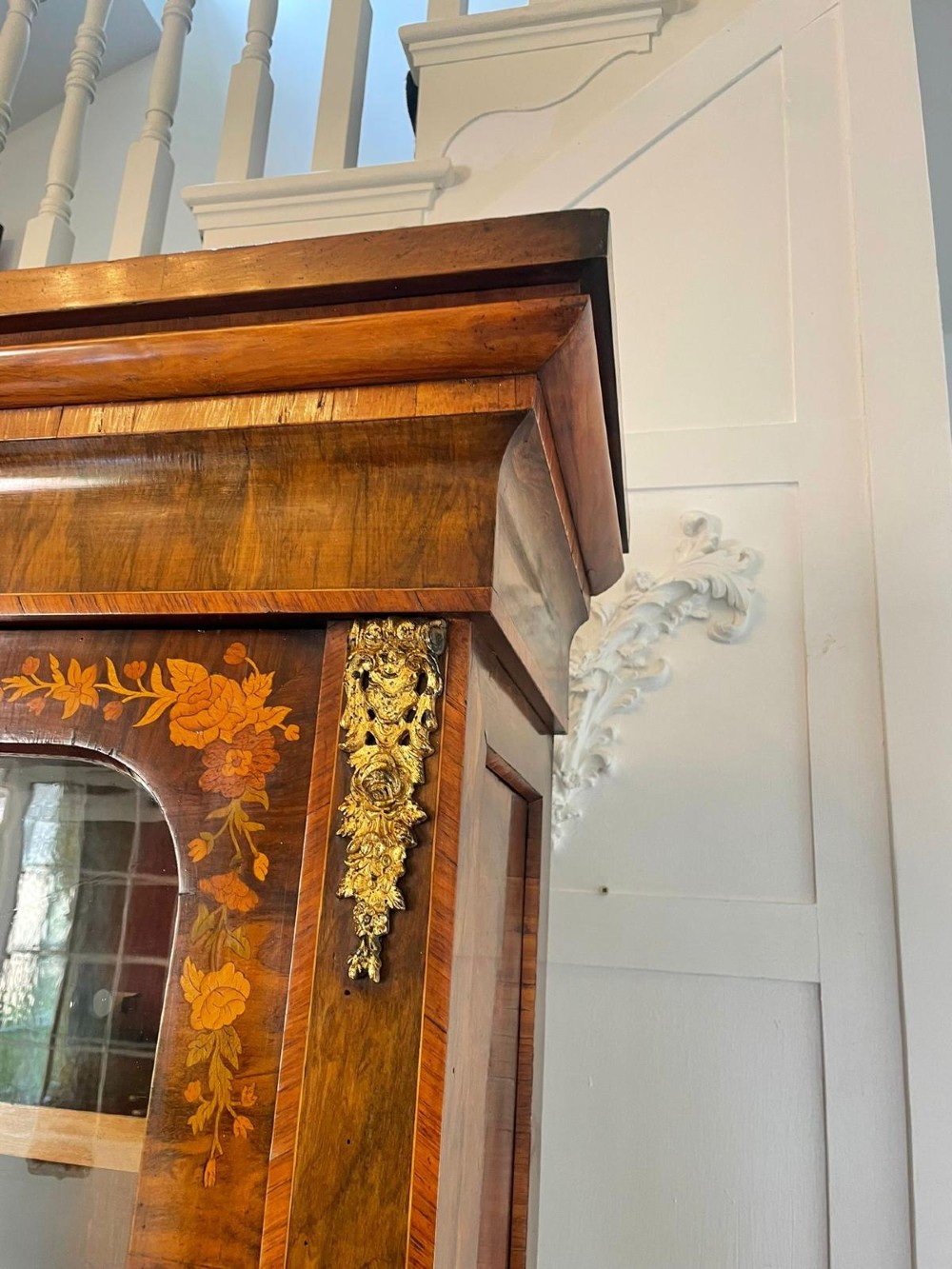 A Victorian two-part burr walnut bookcase cabinet featuring glazed upper doors with floral marquetry inlays and gilt ormolu mounts. View VIII