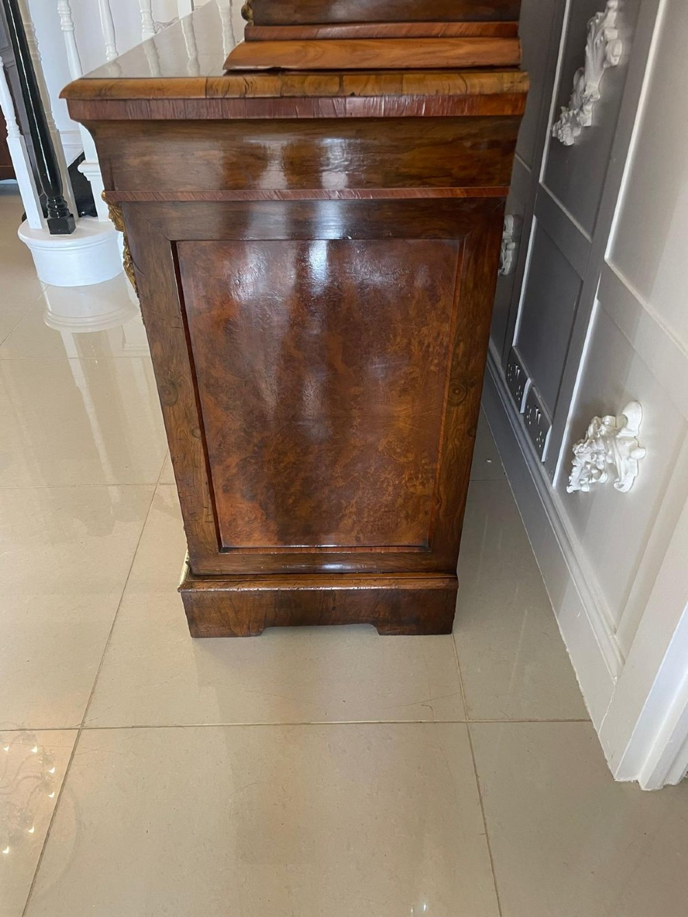 A Victorian two-part burr walnut bookcase cabinet featuring glazed upper doors with floral marquetry inlays and gilt ormolu mounts. View X