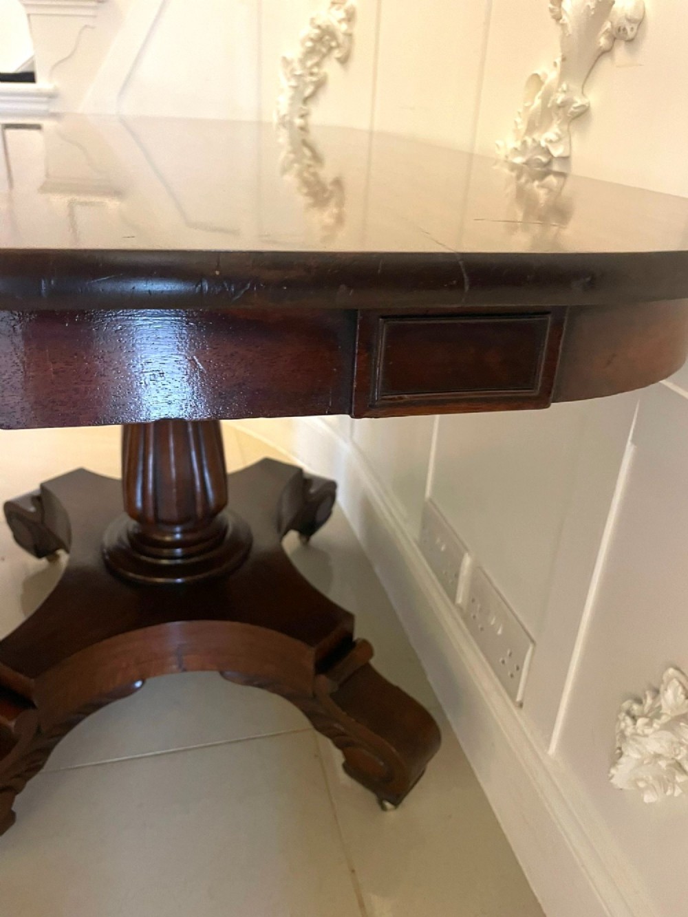 A large polished Regency style mahogany extendable dining table featuring a rounded rectangular top supported by carved pedestal bases on splayed legs. View X