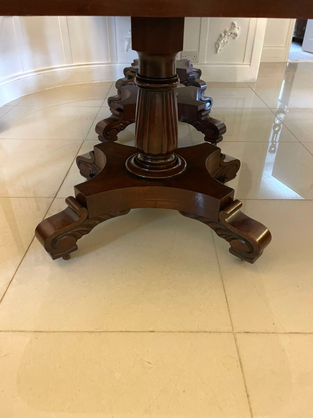 A large polished Regency style mahogany extendable dining table featuring a rounded rectangular top supported by carved pedestal bases on splayed legs. View XI