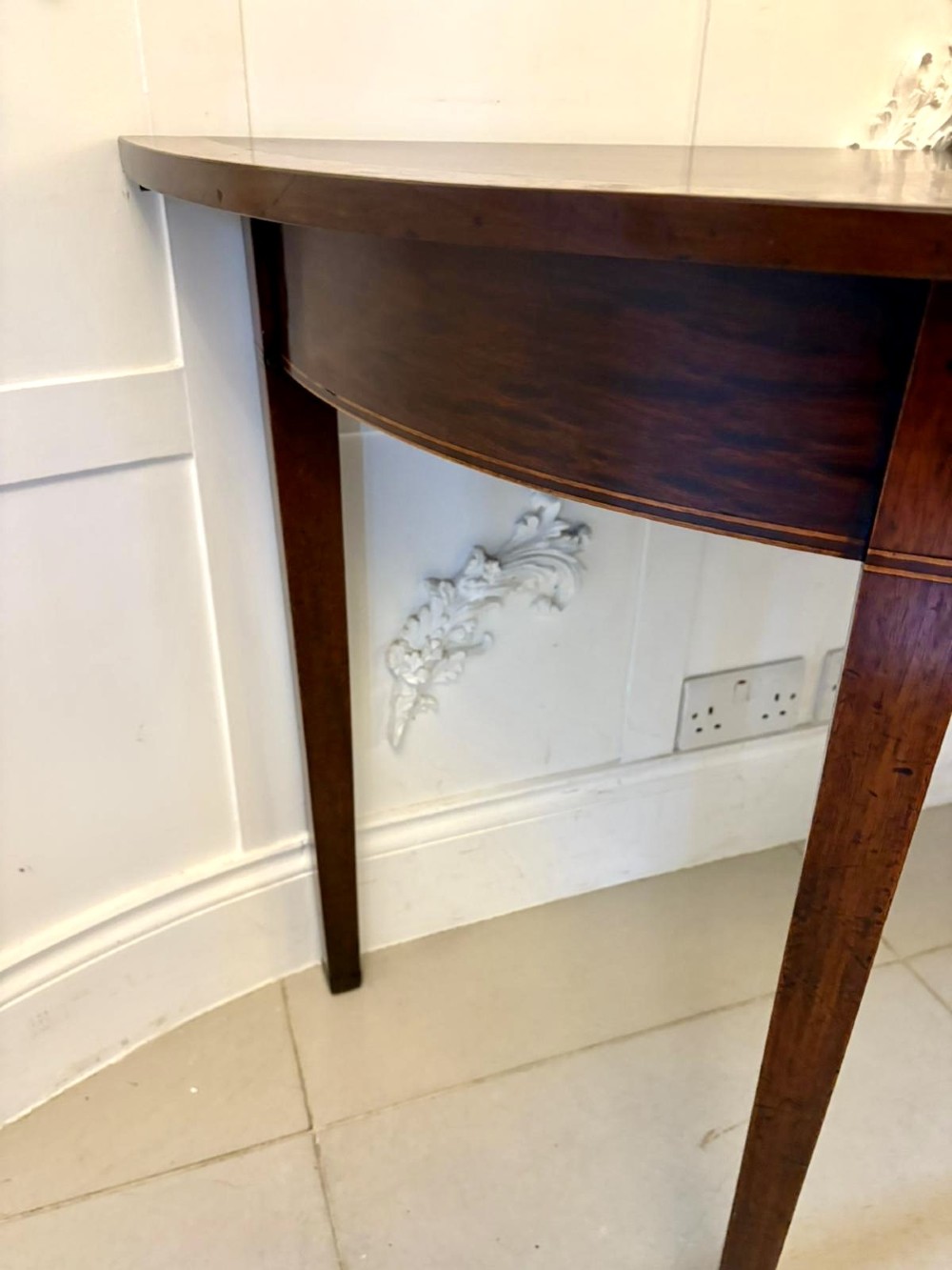A pair of George III semi-circular mahogany console tables featuring crossbanded tops and square tapered legs. View II