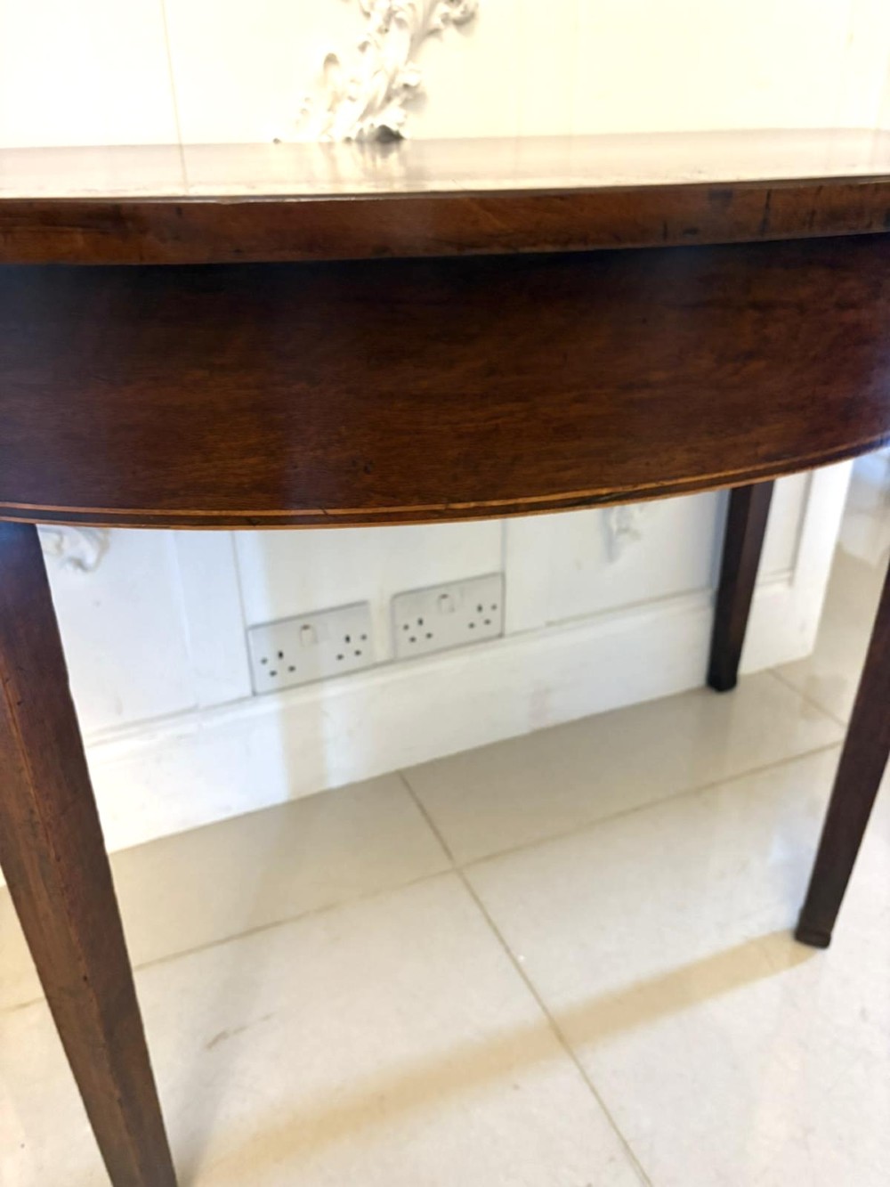 A pair of George III semi-circular mahogany console tables featuring crossbanded tops and square tapered legs. View V