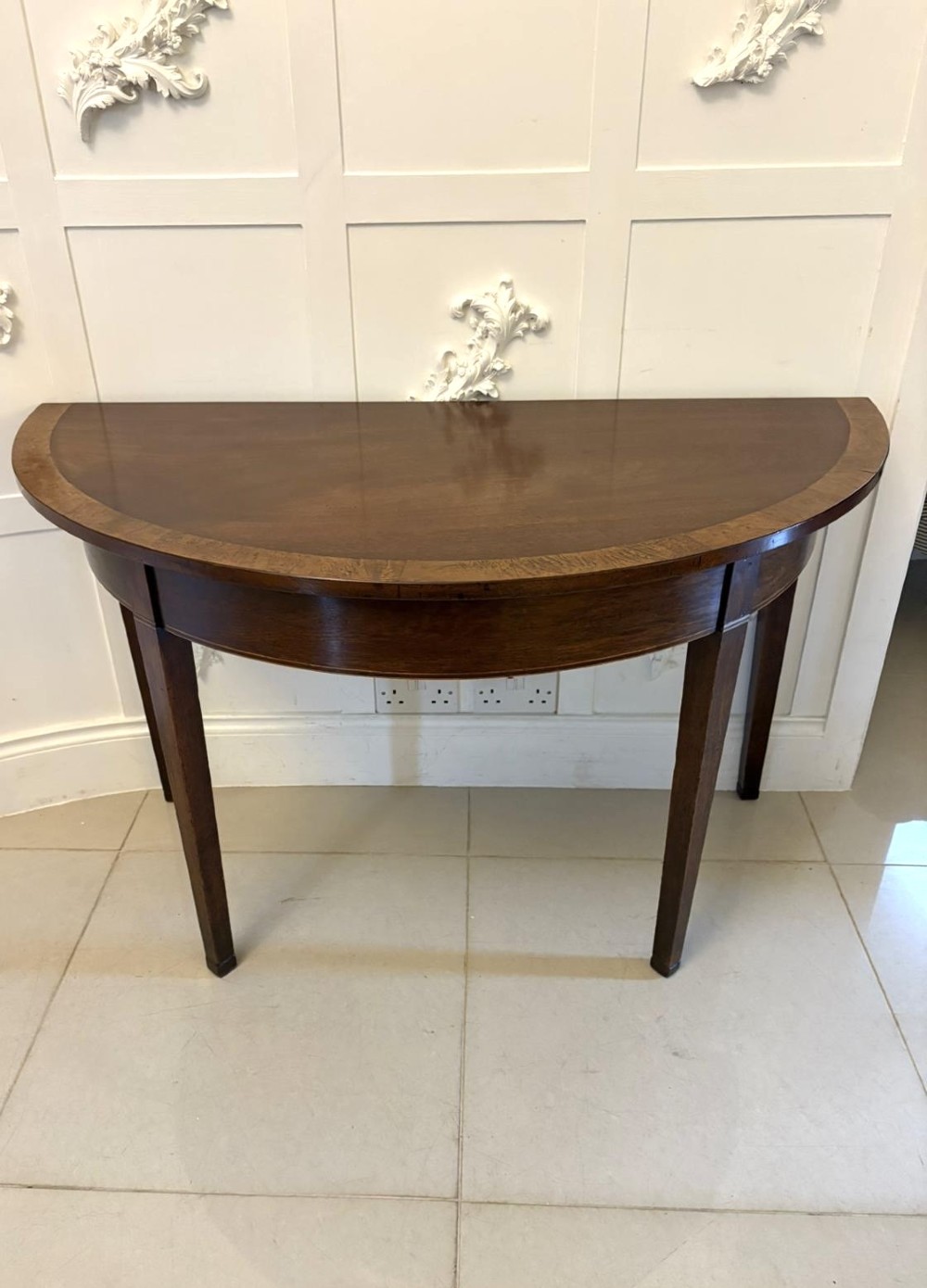 A pair of George III semi-circular mahogany console tables featuring crossbanded tops and square tapered legs. View VII