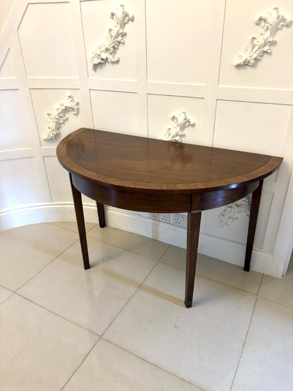 A pair of George III semi-circular mahogany console tables featuring crossbanded tops and square tapered legs. View VIII
