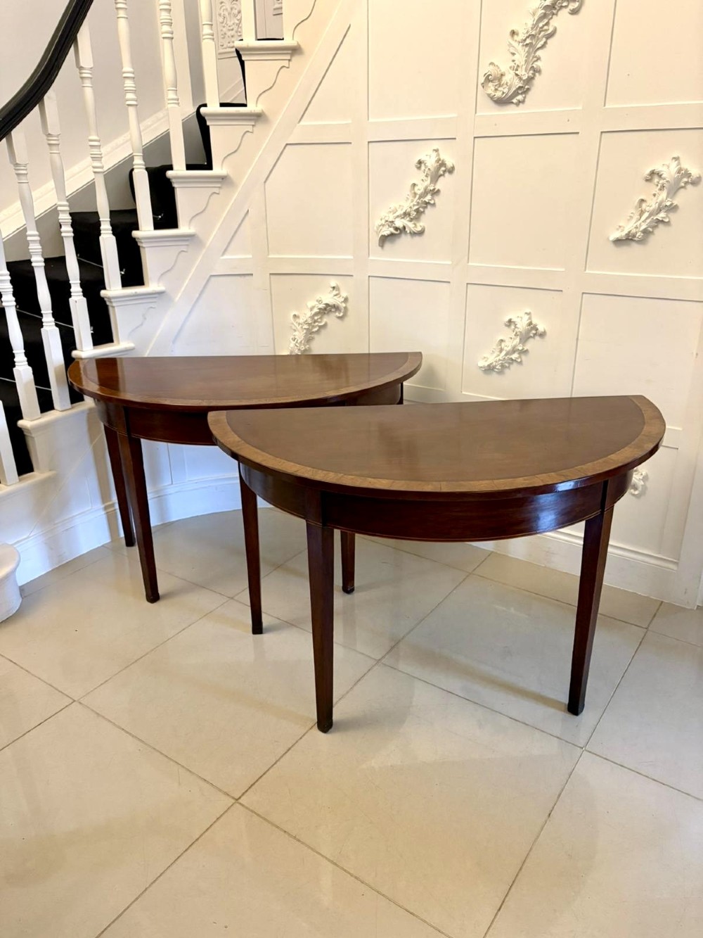 A pair of George III semi-circular mahogany console tables featuring crossbanded tops and square tapered legs. View X