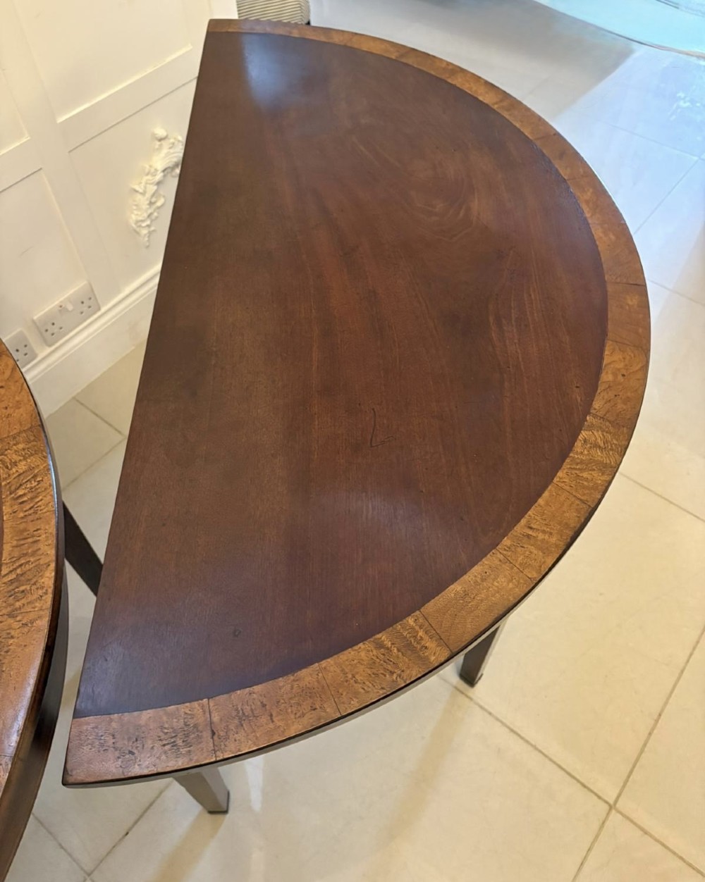A pair of George III semi-circular mahogany console tables featuring crossbanded tops and square tapered legs. View XII