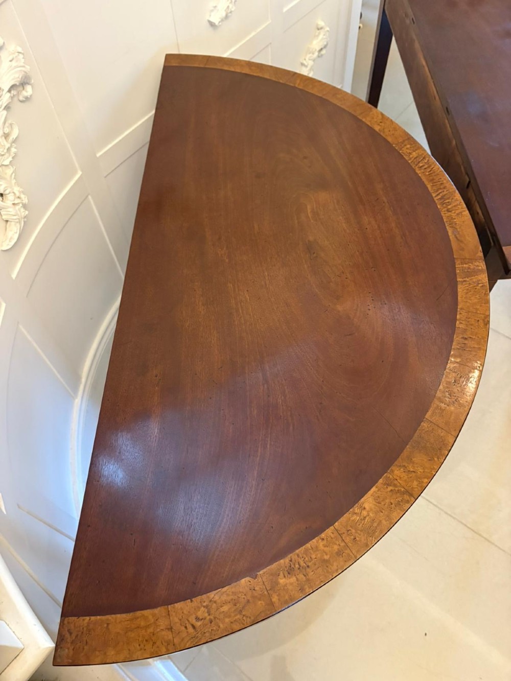 A pair of George III semi-circular mahogany console tables featuring crossbanded tops and square tapered legs. View XIII