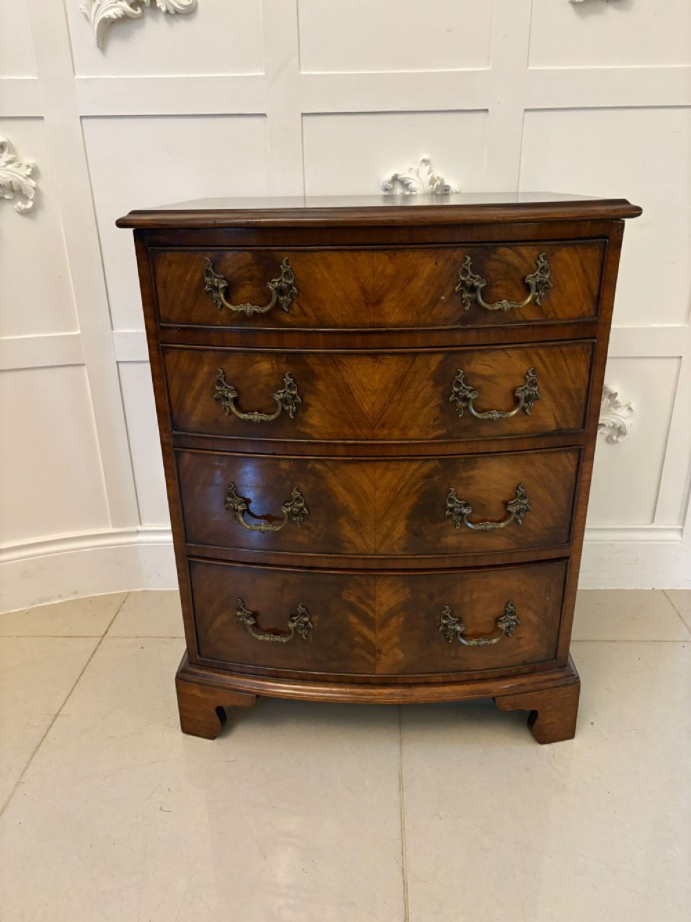 An Edwardian bow-fronted mahogany chest with four drawers, decorative brass handles, and flame veneer drawer fronts set on bracket feet. View III
