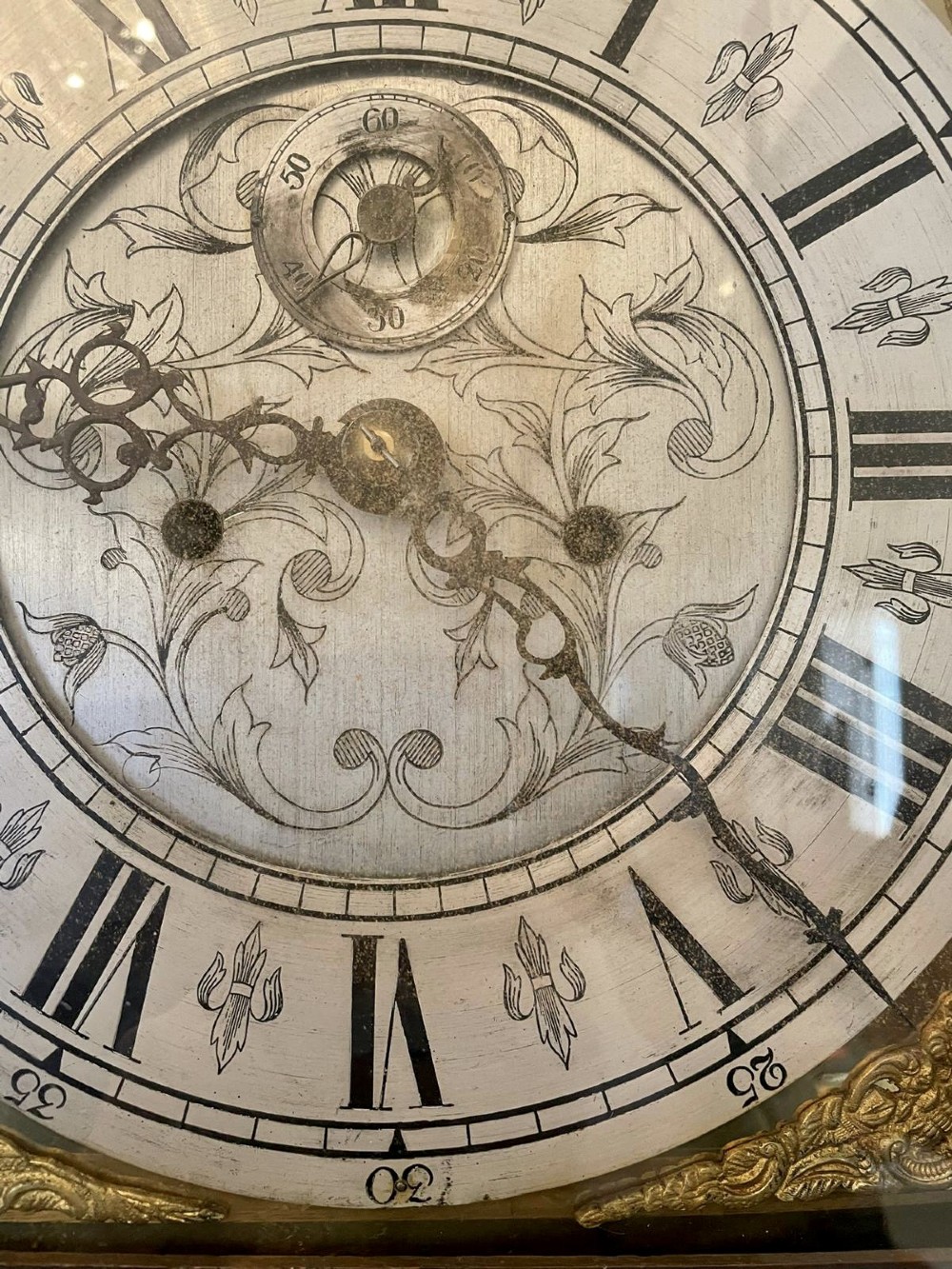 A George III oak longcase clock featuring an etched brass dial with silvered chapter ring, inlaid wood motif pediment, and an arched trunk door. View III