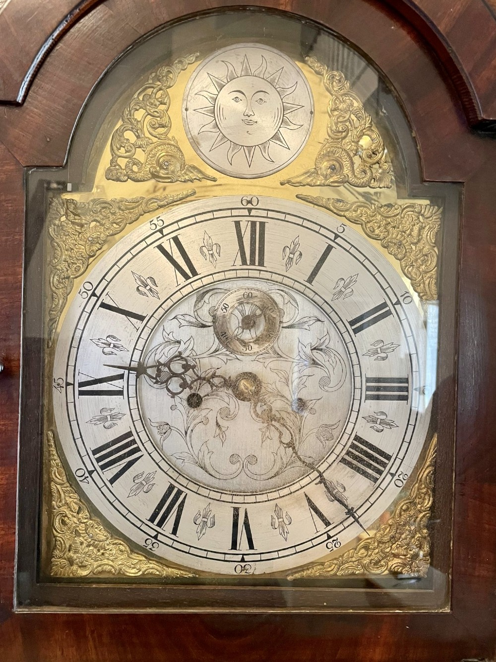 A George III oak longcase clock featuring an etched brass dial with silvered chapter ring, inlaid wood motif pediment, and an arched trunk door. View VI