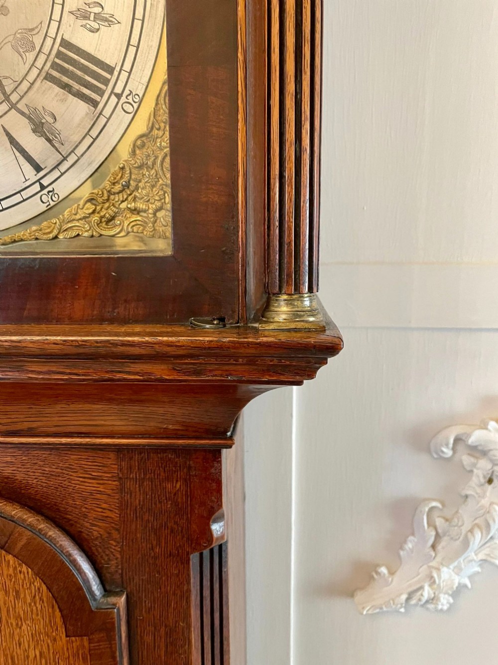 A George III oak longcase clock featuring an etched brass dial with silvered chapter ring, inlaid wood motif pediment, and an arched trunk door. View XIII