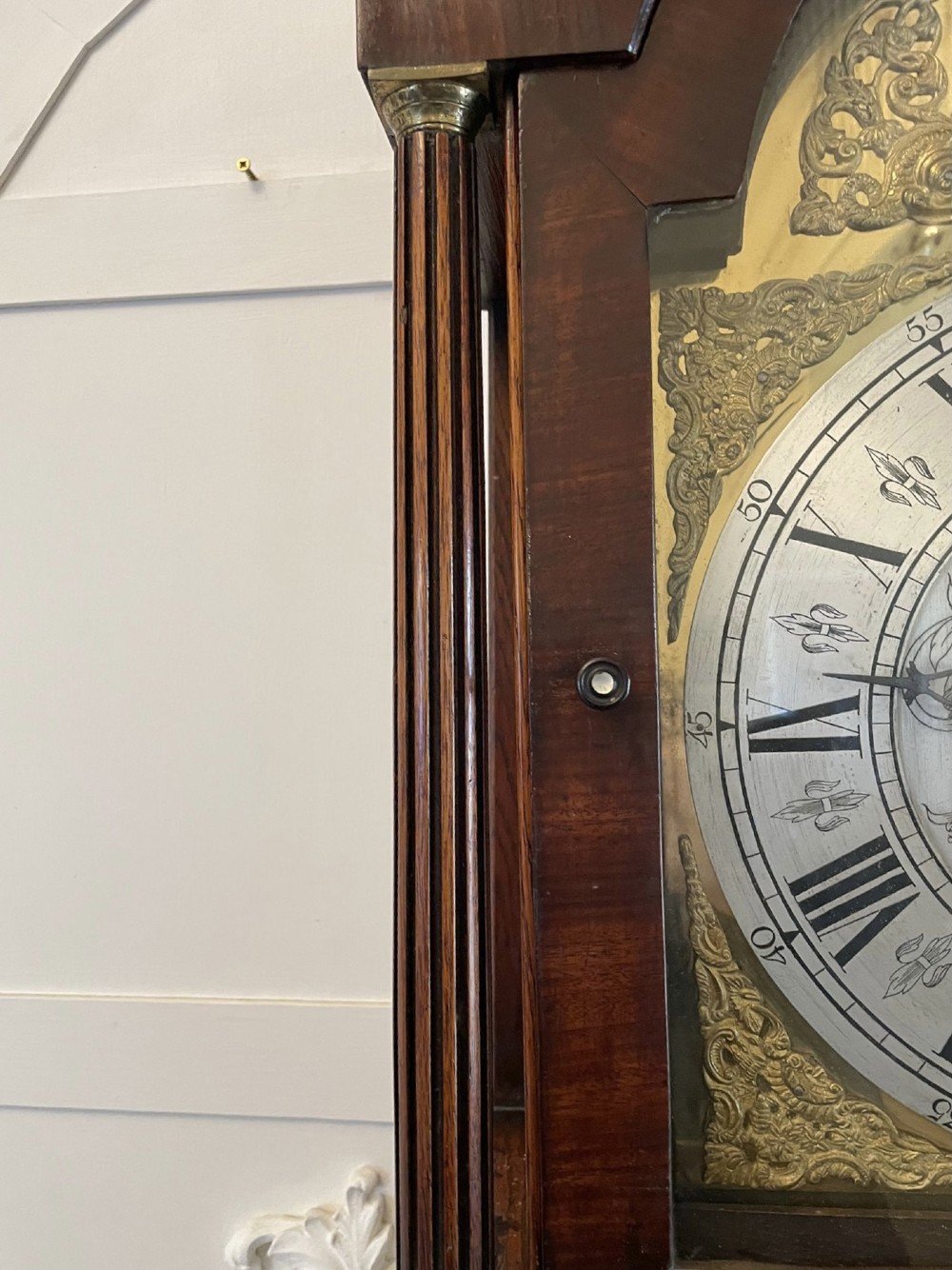 A George III oak longcase clock featuring an etched brass dial with silvered chapter ring, inlaid wood motif pediment, and an arched trunk door. View XV
