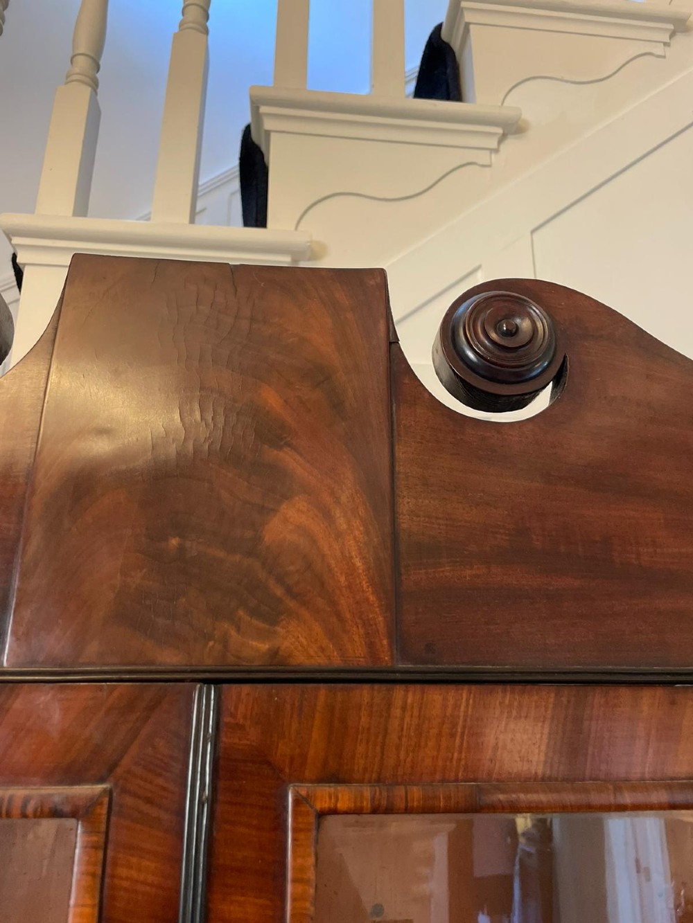 An antique Regency mahogany secretaire bookcase featuring a top scroll pediment, glazed upper doors with astragal moulding, and a lower double cupboard. View VI