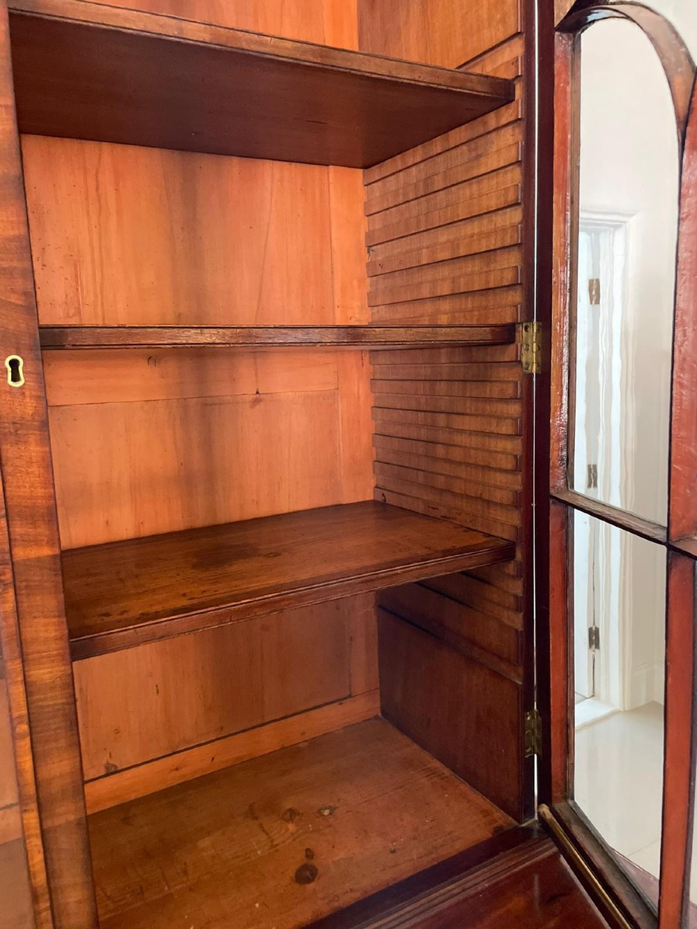 An antique Regency mahogany secretaire bookcase featuring a top scroll pediment, glazed upper doors with astragal moulding, and a lower double cupboard. View VII