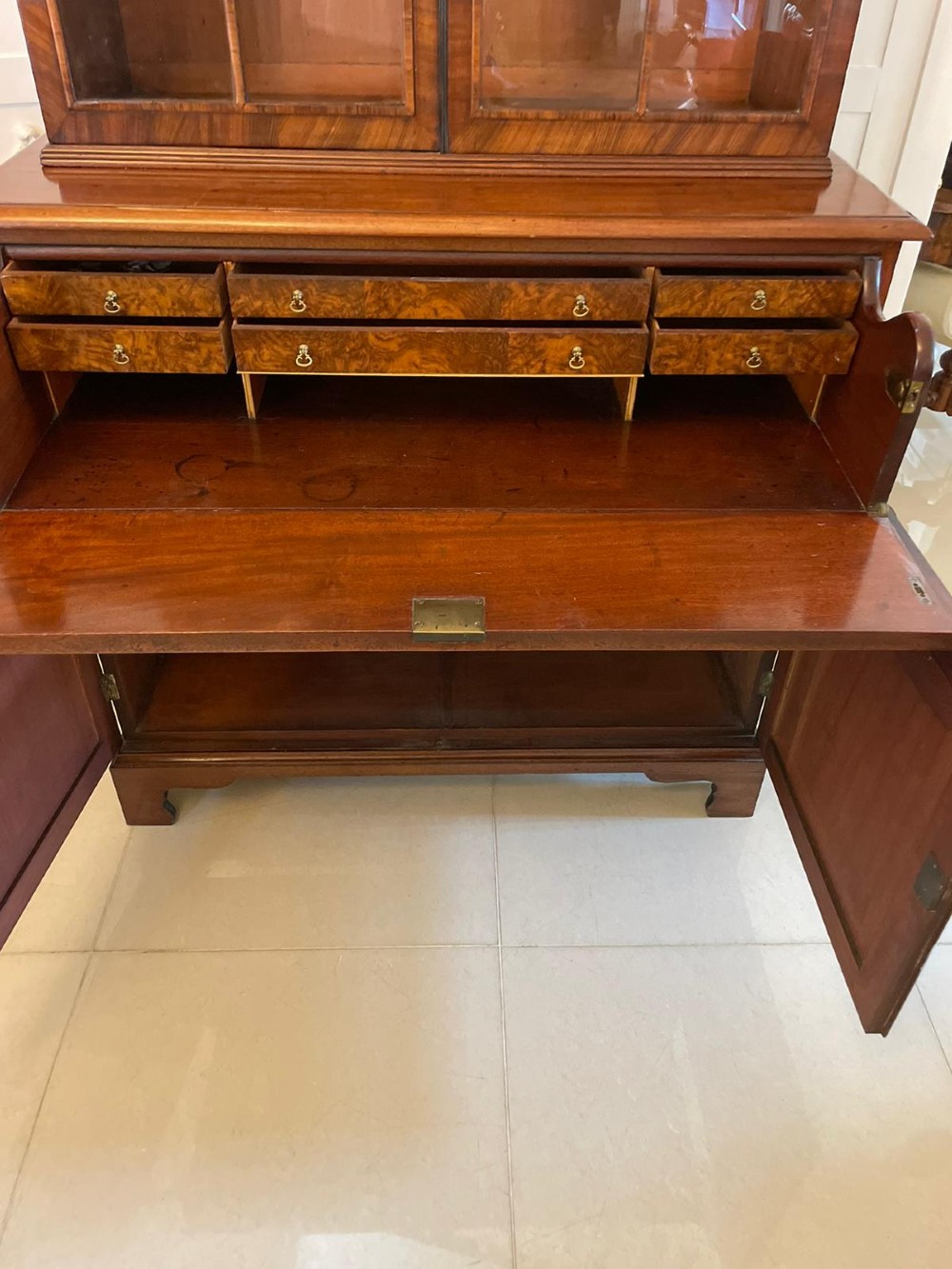 An antique Regency mahogany secretaire bookcase featuring a top scroll pediment, glazed upper doors with astragal moulding, and a lower double cupboard. View IX