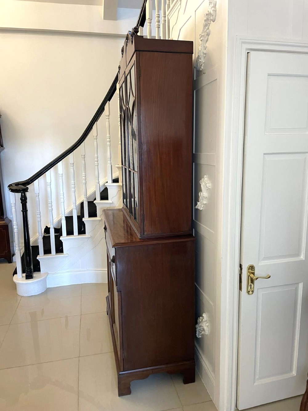 An antique Regency mahogany secretaire bookcase featuring a top scroll pediment, glazed upper doors with astragal moulding, and a lower double cupboard. View XV
