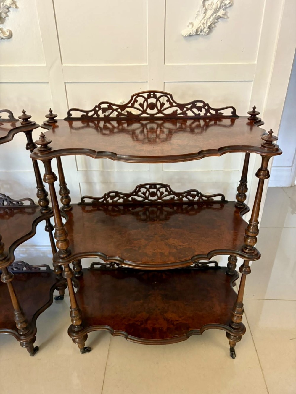 A pair of Victorian burr walnut three-tier whatnots featuring pierced fretwork galleries, serpentine fronts, and turned upright supports on castors. View XII
