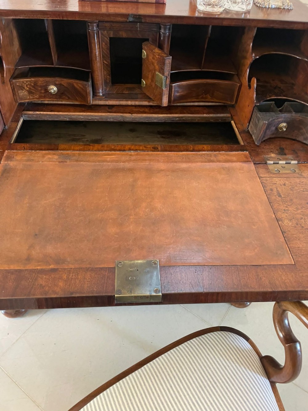 An antique burr walnut slant-front bureau featuring herringbone inlay, brass hardware, three lower drawers, and turned bun feet. View IV