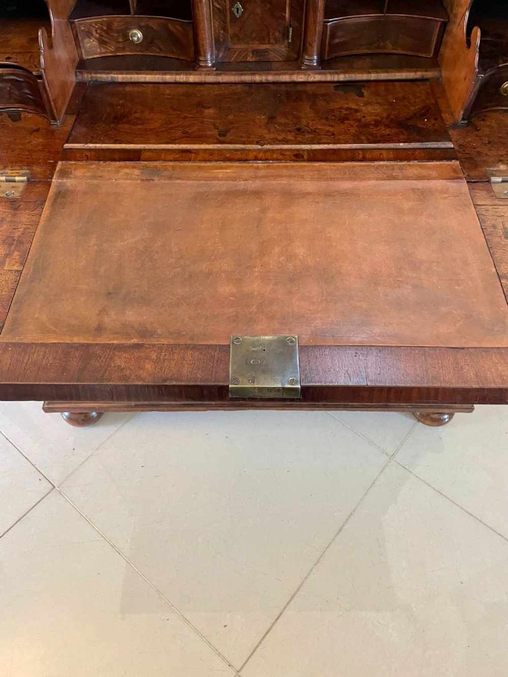 An antique burr walnut slant-front bureau featuring herringbone inlay, brass hardware, three lower drawers, and turned bun feet. View VII