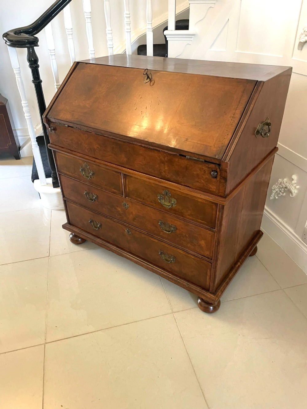 An antique burr walnut slant-front bureau featuring herringbone inlay, brass hardware, three lower drawers, and turned bun feet. View VIII