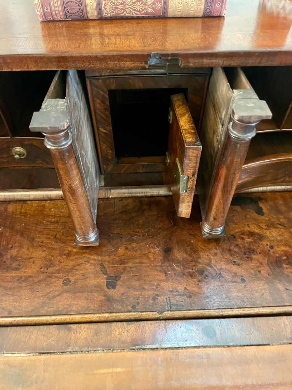 An antique burr walnut slant-front bureau featuring herringbone inlay, brass hardware, three lower drawers, and turned bun feet. View X