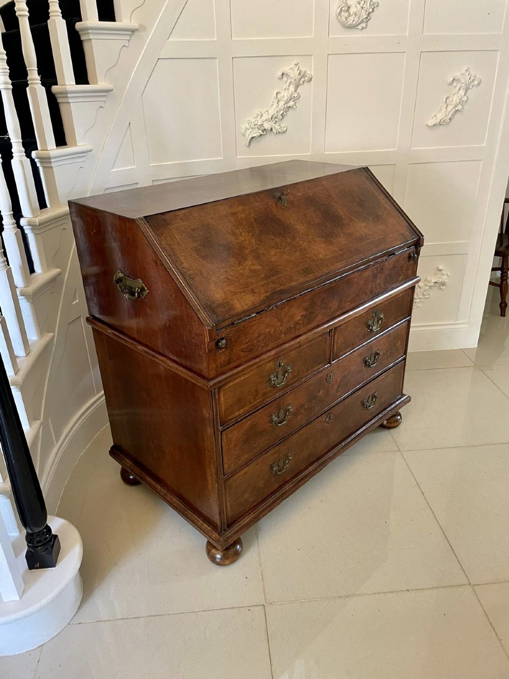 An antique burr walnut slant-front bureau featuring herringbone inlay, brass hardware, three lower drawers, and turned bun feet. View XIII