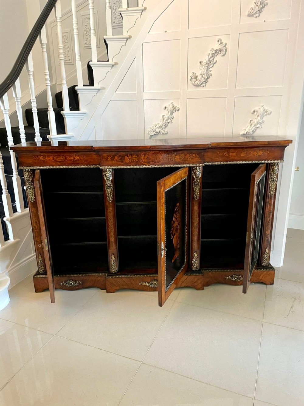 A Victorian burr walnut breakfront credenza featuring brass mounts, a central floral marquetry panel, and mirrored side doors. View V
