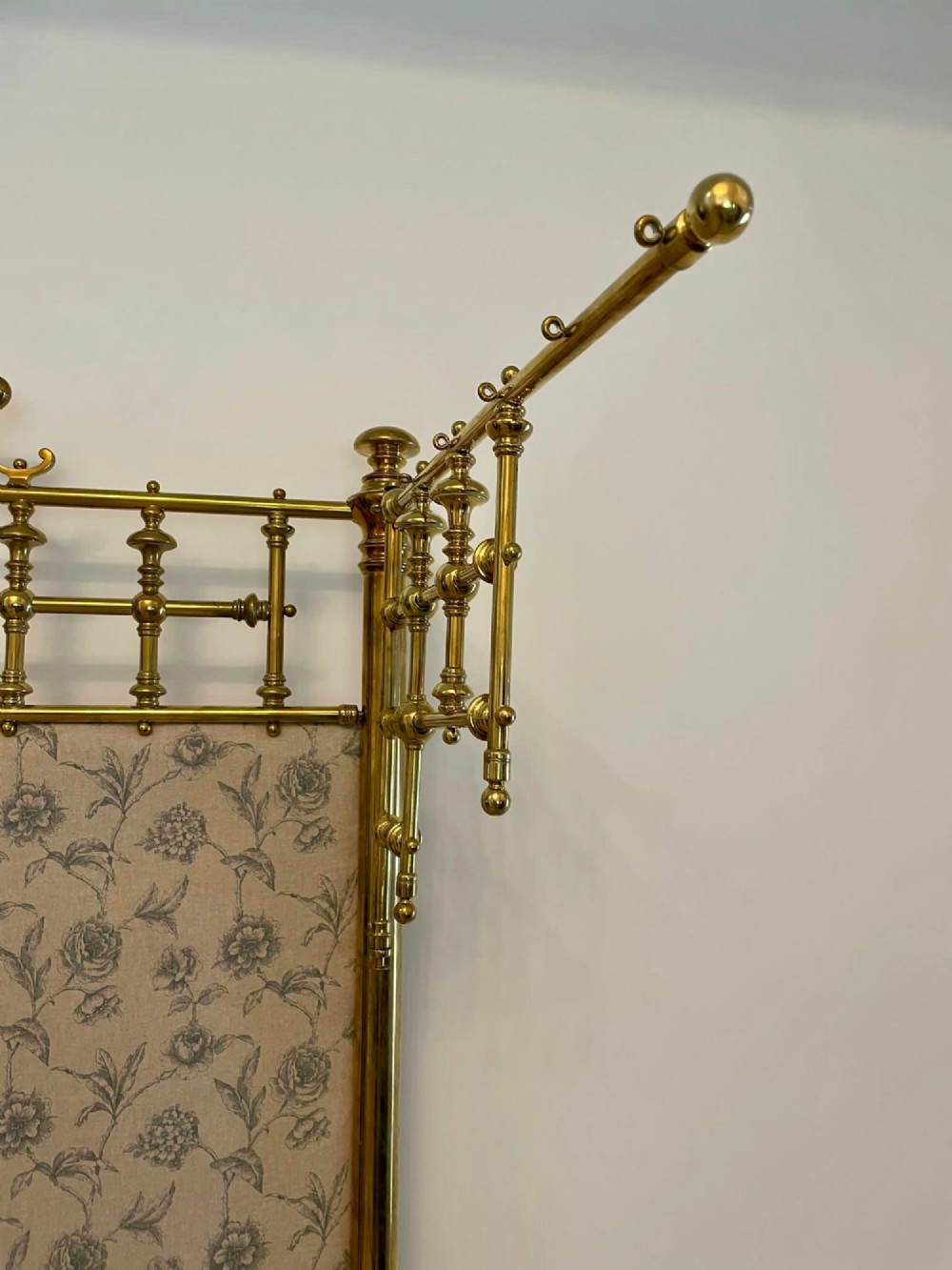 An antique Victorian solid brass half tester double bed featuring turned posts, spindle balusters, cast decorative mounts, and an upholstered floral panel. View VIII