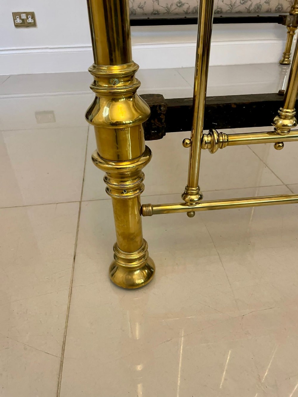 An antique Victorian solid brass half tester double bed featuring turned posts, spindle balusters, cast decorative mounts, and an upholstered floral panel. View X