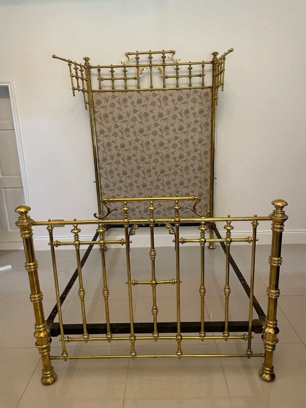 An antique Victorian solid brass half tester double bed featuring turned posts, spindle balusters, cast decorative mounts, and an upholstered floral panel. View XI