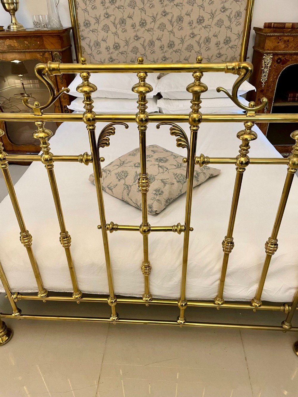 An antique Victorian solid brass half tester double bed featuring turned posts, spindle balusters, cast decorative mounts, and an upholstered floral panel. View XIII