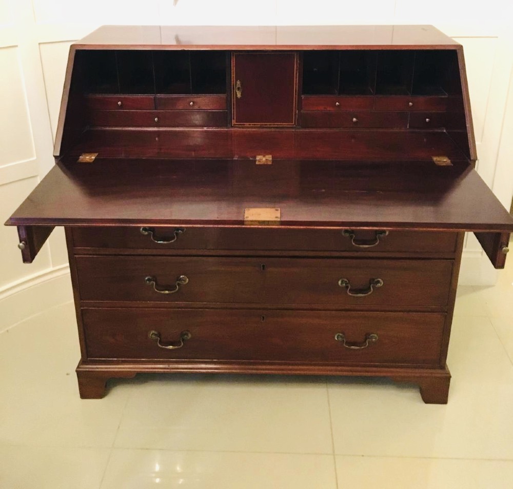 A George III mahogany bureau featuring a sloping fall-front top above four graduated long drawers with brass swan-neck handles, resting on bracket feet. View IX