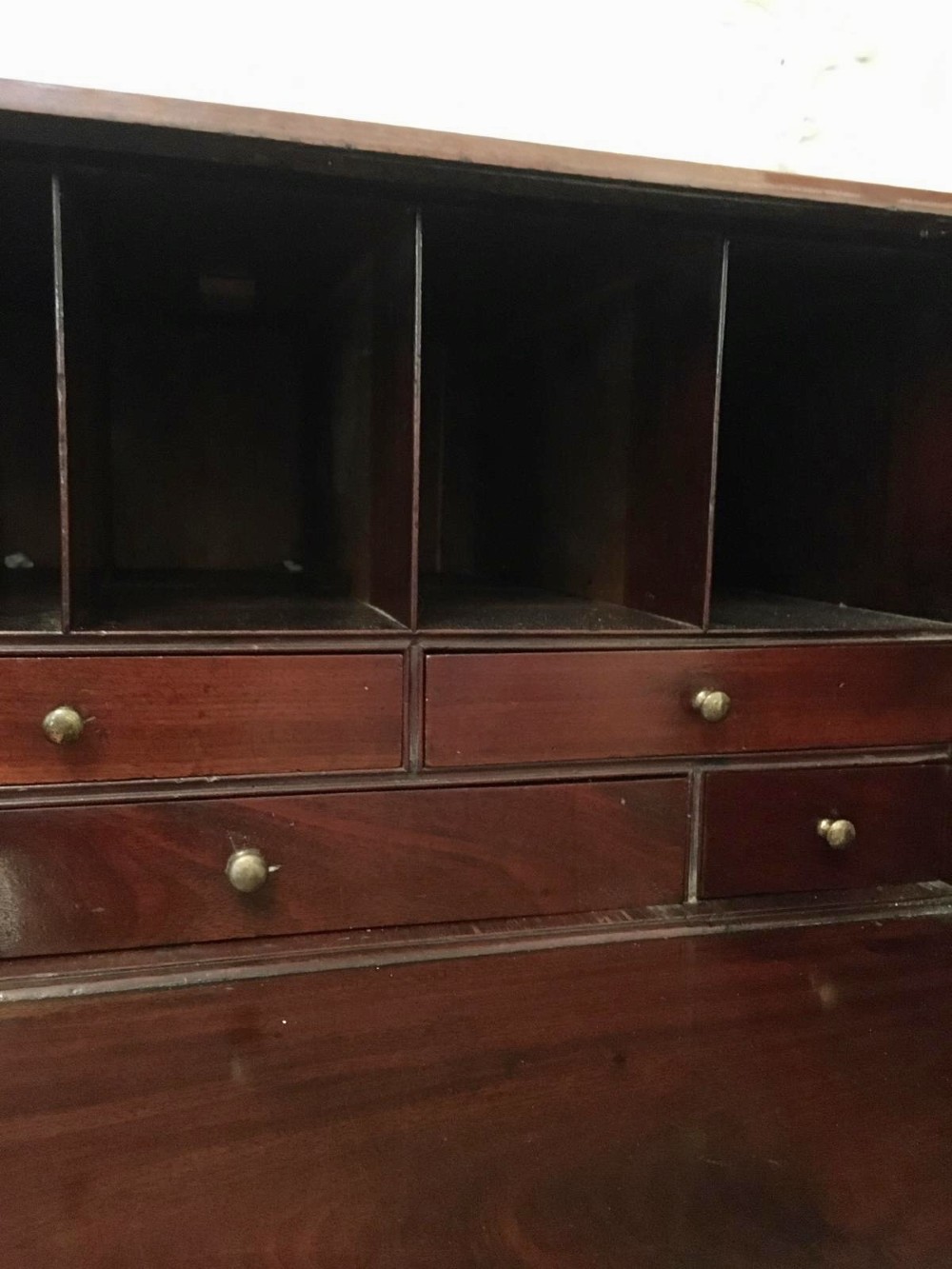 A George III mahogany bureau featuring a sloping fall-front top above four graduated long drawers with brass swan-neck handles, resting on bracket feet. View XI