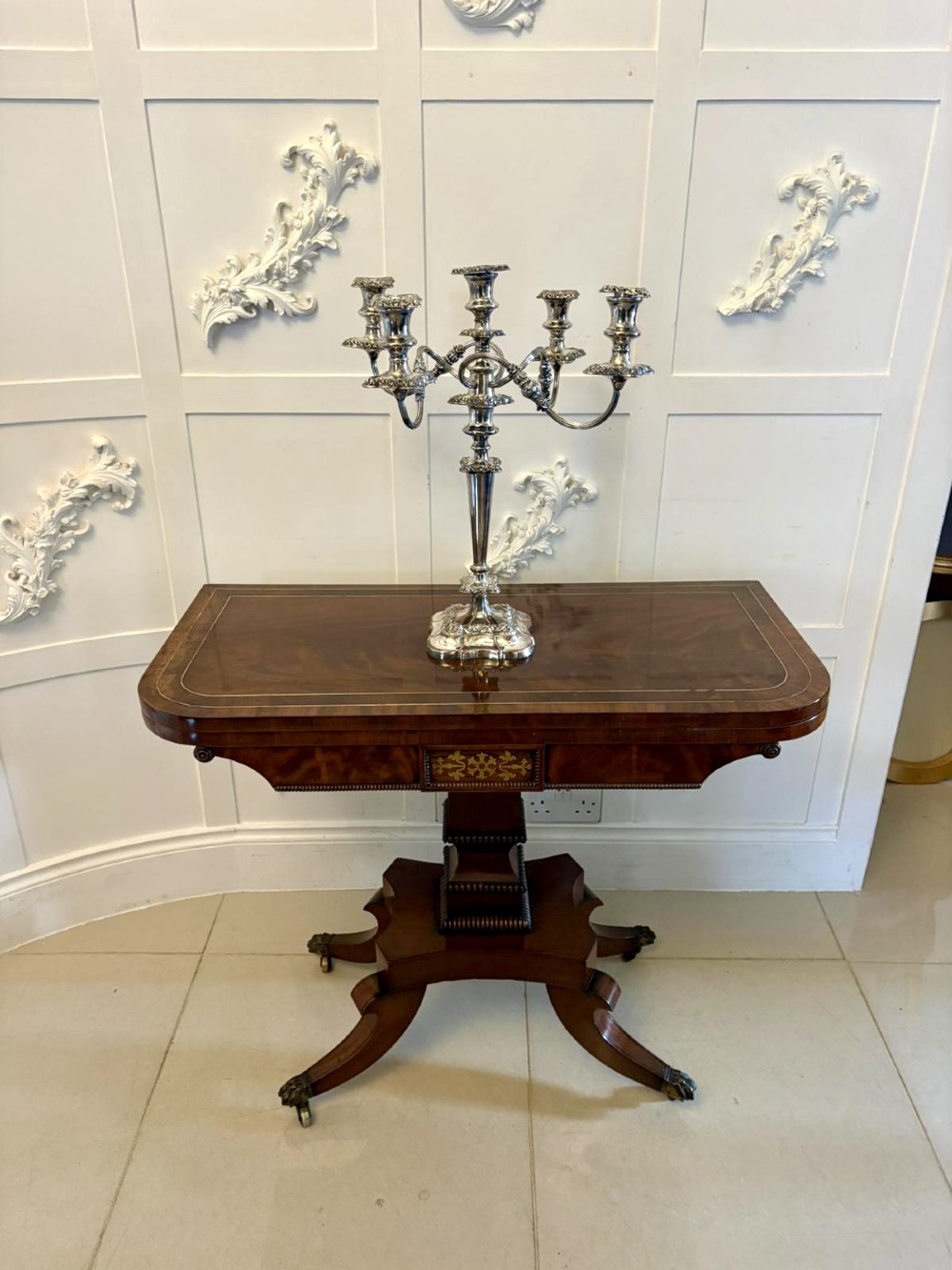 An antique Regency mahogany fold-over card table featuring brass marquetry inlay, a central shaped pedestal, and a splayed base with brass castors. View III