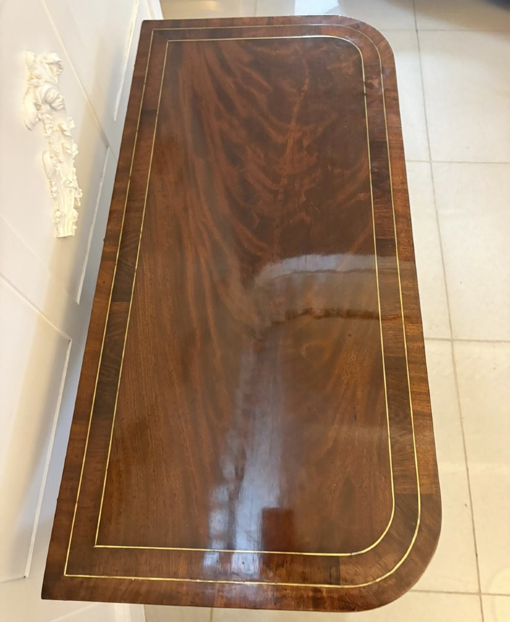 An antique Regency mahogany fold-over card table featuring brass marquetry inlay, a central shaped pedestal, and a splayed base with brass castors. View XIII