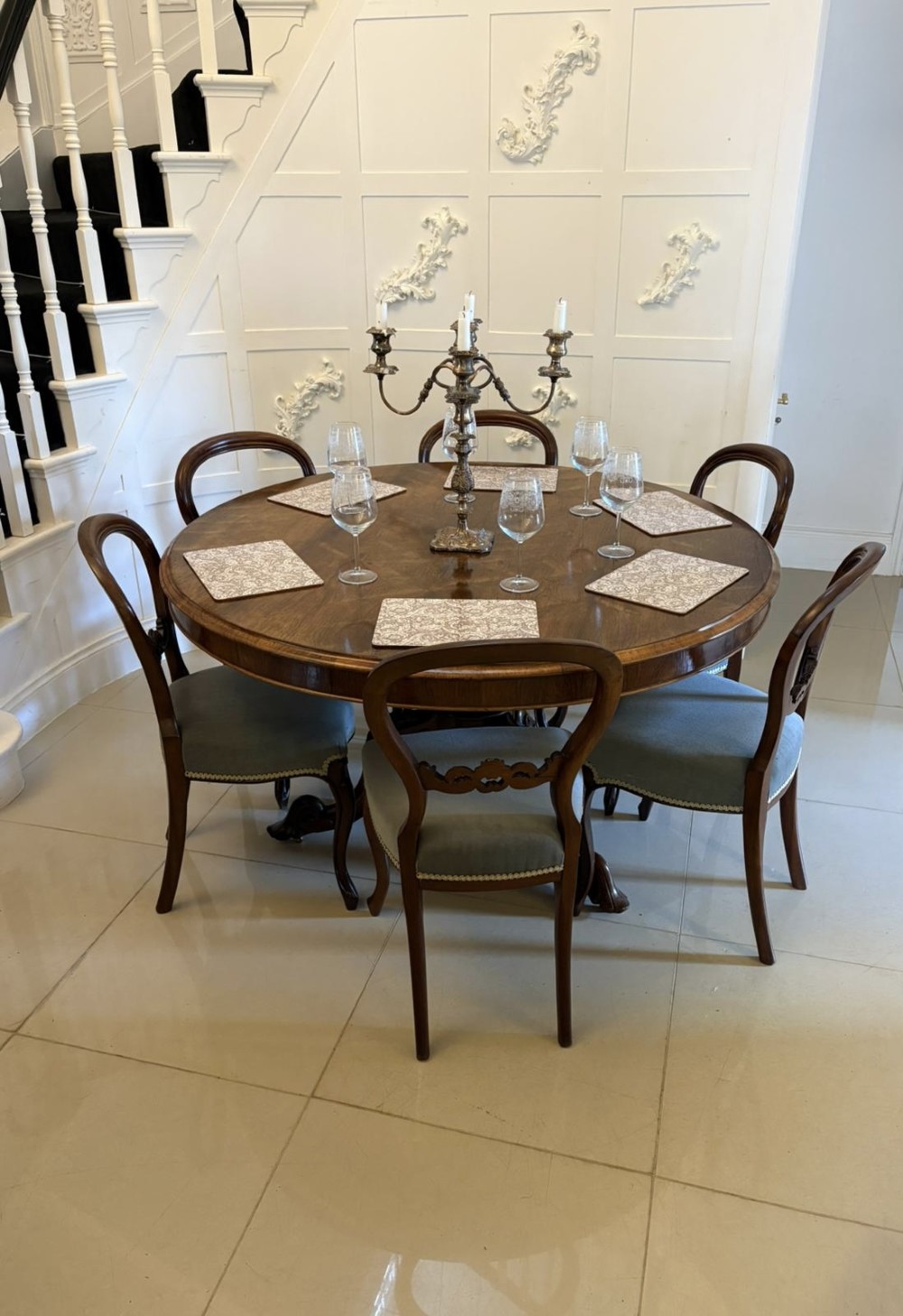 A Victorian circular rosewood dining table with a matched grain veneer top, shown tilted vertically on a carved pedestal base with scroll feet. View V