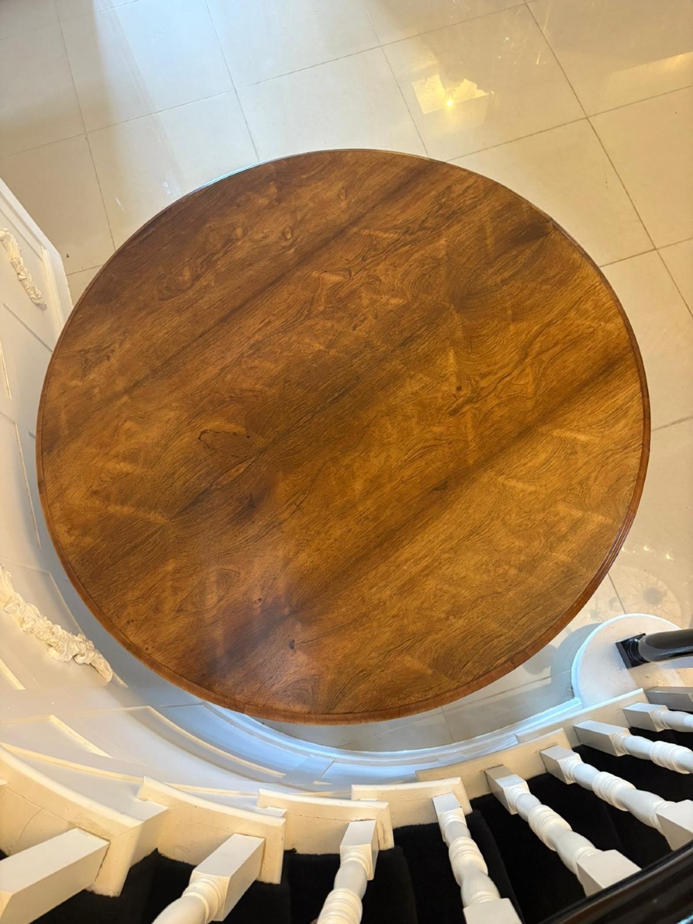 A Victorian circular rosewood dining table with a matched grain veneer top, shown tilted vertically on a carved pedestal base with scroll feet. View VI