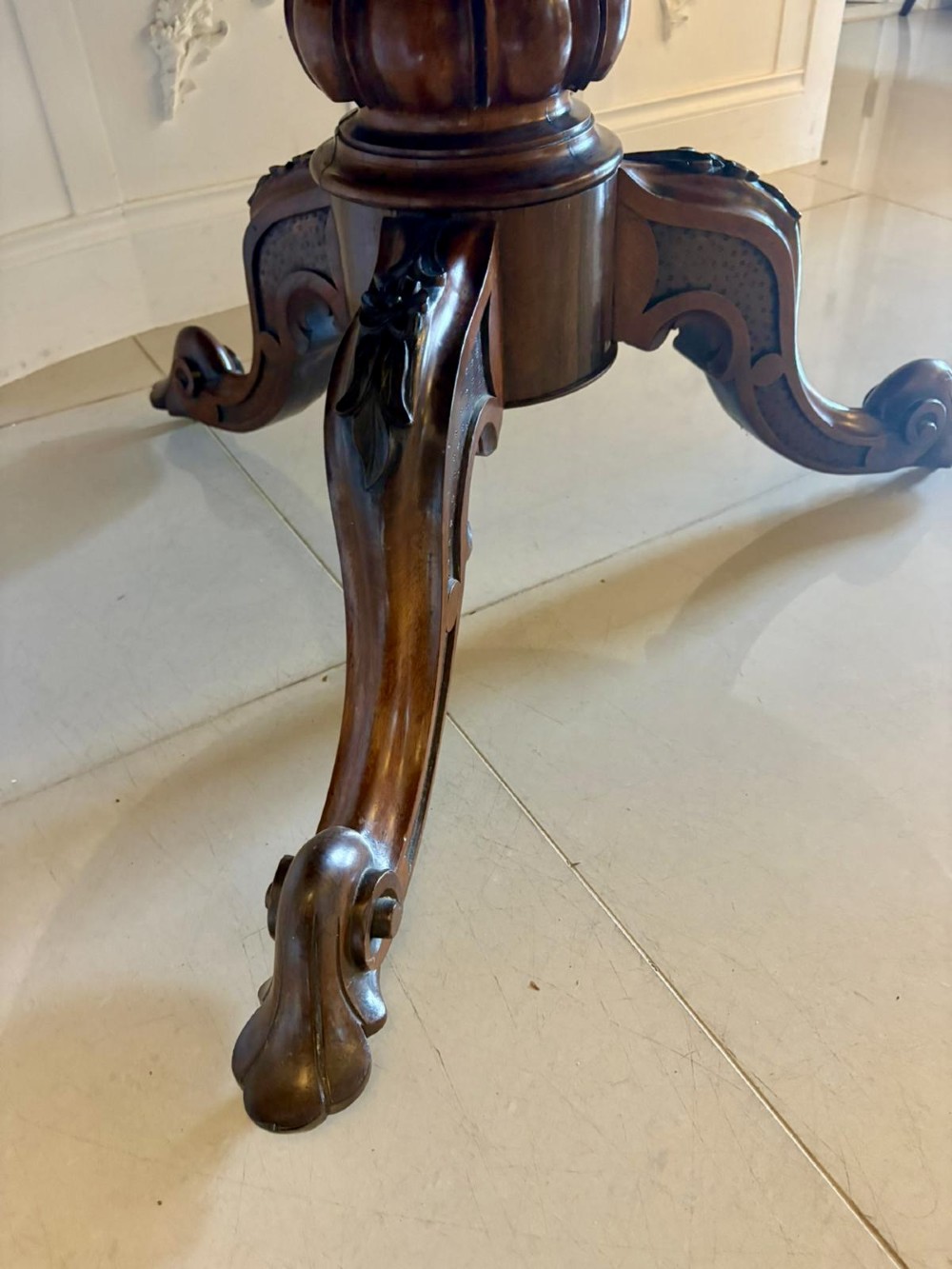 A Victorian circular rosewood dining table with a matched grain veneer top, shown tilted vertically on a carved pedestal base with scroll feet. View VII